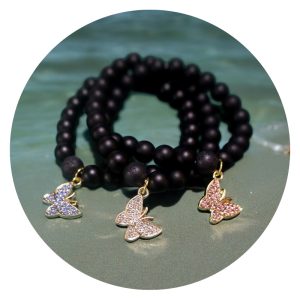 Armband met gladde zwarte kralen en goudkleurig vlindertje