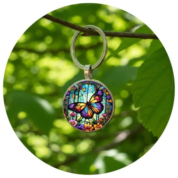 sleutelhangen met kleurrijke vlinder hangend aan een boomtak tussen groen gebladerte.